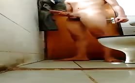 Horny young latin guy stroking his fat cock in the toilet
